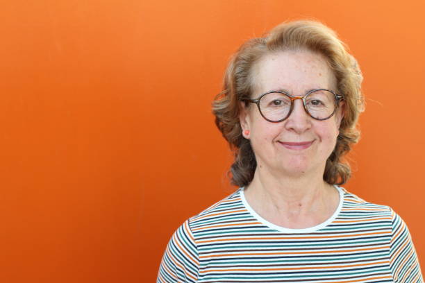 Blonde senior woman in orange background