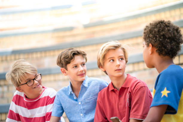 istock Boy talking with friends on steps at school 1169906606