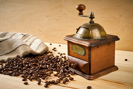 old coffee grinder on a wooden table with seeds