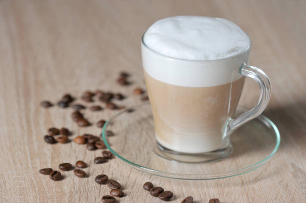 istock Cappuccino in a transparent cup on a light surface. Coffee beans on the surface of the table. Close-up. 1169913848