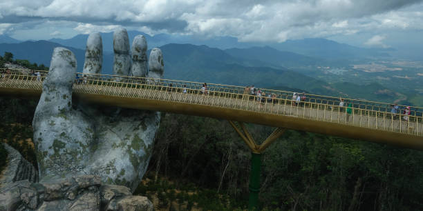 Golden Bridge, Danang, Vietnam Danang, Vietnam - August 18, 2018: Tourists in the Golden Bridge. The Golden Bridge is a 150 m long pedestrian bridge in the Ba Na Hills in Danang. bridge hand stock pictures, royalty-free photos & images