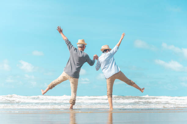 encantadora pareja de ancianos fue a la playa para disfrutar de la brisa del mar - healthy lifestyle women jumping happiness fotografías e imágenes de stock