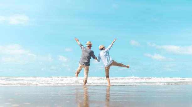 charmantes älteres paar ging an den strand, um die meeresbrise zu genießen - smart casual outdoors friendship happiness stock-fotos und bilder