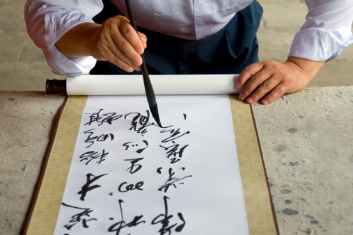 A Chinese calligrapher at work writing on a scroll