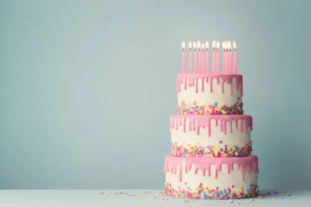 Tiered birthday cake with drip frosting and twelve candles