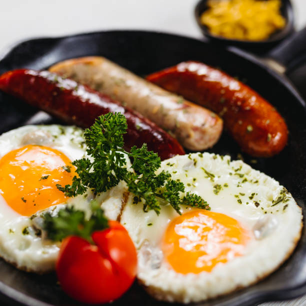 istock Fried eggs sunny side up served with sausage in a cooking pan 1169921244