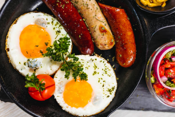 istock Fried eggs sunny side up served with sausage in a cooking pan 1169923988