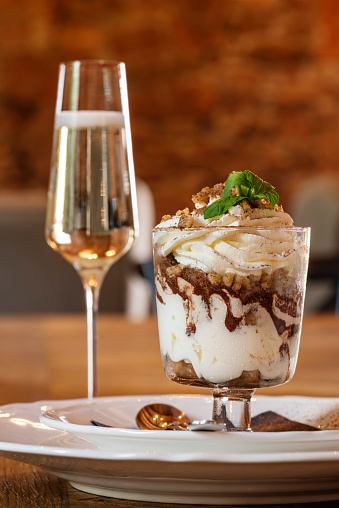 Italian dessert tiramisu and a glass of wine on a table in cafe