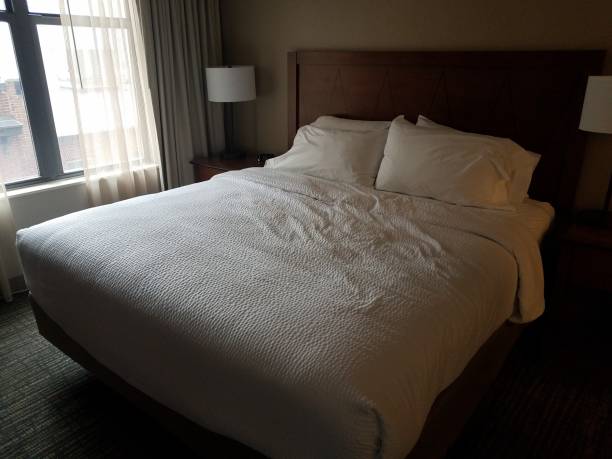 istock bed in room with white covers and lights and window 1169927780