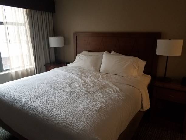 istock bed in room with white covers and lights and window 1169927795