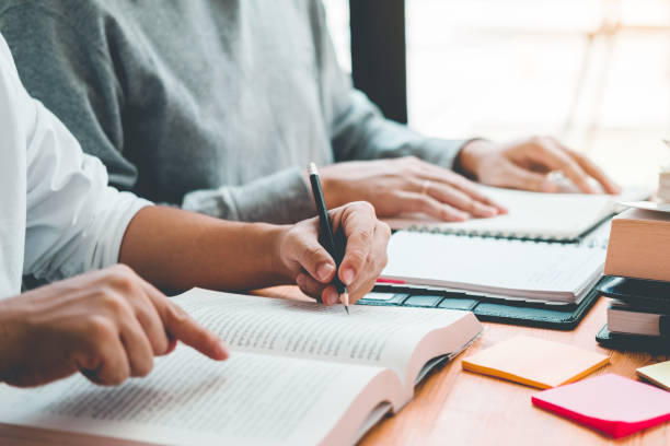 istock University students or college students studying and reading together in library. 1169929329