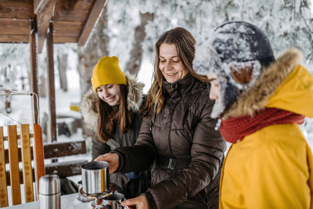 Family drinking tea outdoors at winter time Mother with her two children drinking tea outdoors at winter time. They after the sledding drinking hot drink from travel mug cups. 12 17 months stock pictures, royalty-free photos & images