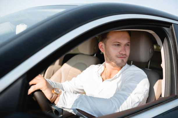 retrato de um excitador feliz em uma camisa branca que conduz seu carro luxary. - luxary - fotografias e filmes do acervo