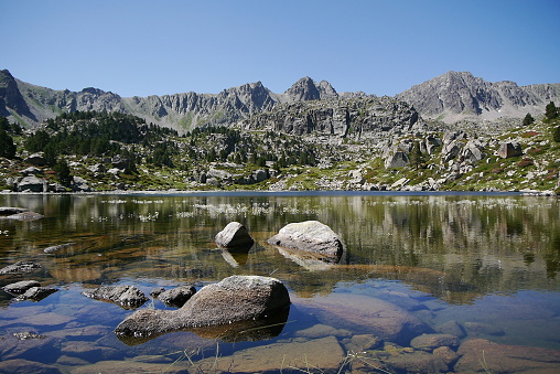 Clear lake with picturesque alpine scenery of mountains of the Pyrenees in the background of the landscape