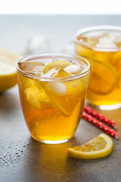 Cold tea with lemon and ice in a glass with drops, fresh sweet fruit drink, summer freshness, delicious lemonade stock photo