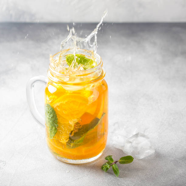 Cold tea with orange, mint and ice, sweet summer drink, refreshing lemonade, juicy cocktail. Spray, splash stock photo