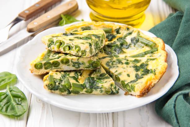 Omelet with spinach and green beans, healthy food. Egg and milk Frittata, delicious Breakfast on white wooden background stock photo