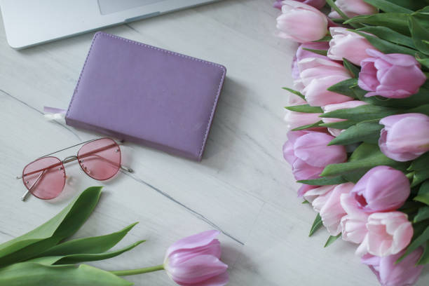 istock Laptop on white floor with flowers. tulips 1169944576
