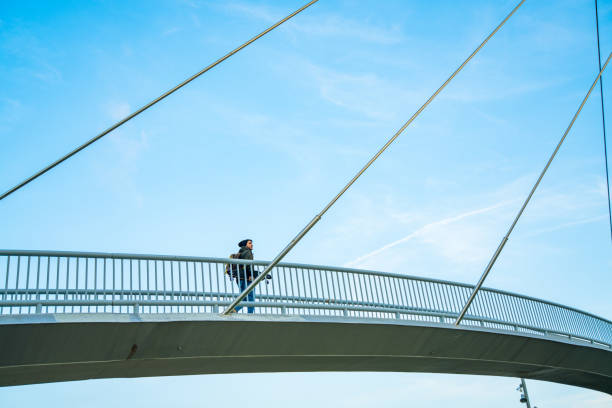 Cool young man carrying a longboard in an elevated walkway Cool young man carrying a longboard in an elevated walkway people on bridge stock pictures, royalty-free photos & images
