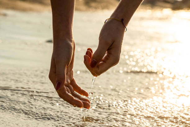 Hands of a girl playing with sea water at dawn stock photo