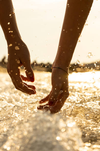 Hands of a girl playing with sea water at dawn stock photo