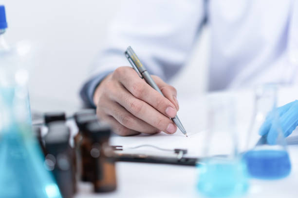 researcher in the laboratory studying with chemicals and microscopes - medical exam science research scientific experiment imagens e fotografias de stock