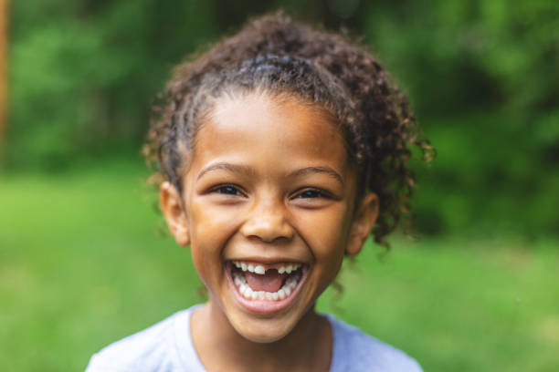 sechsjährige afroamerikanische chinesische ethnizität mädchen posiert für porträt in üppigen grünen outdoor-hinterhof-einstellung - laughing children stock-fotos und bilder