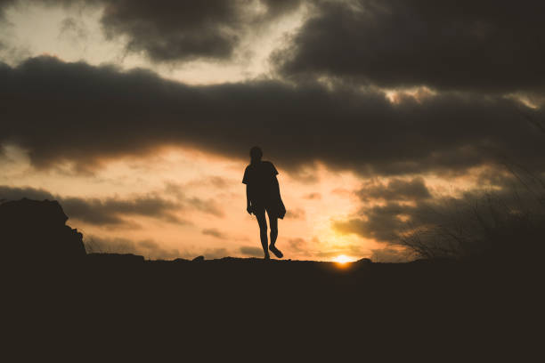istock silhouette of lonely person walking with sunset 1169950700