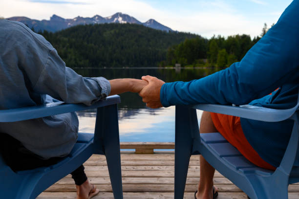istock Couple holding hands while relaxing at lake 1169951918