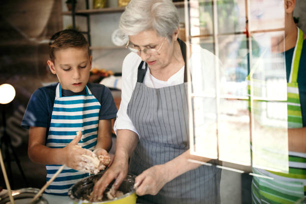 Kids playing with their grandmother in kitchen, making a cake