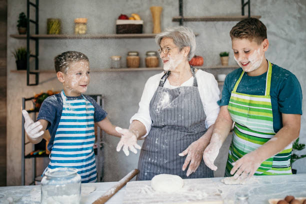 istock Kids playing with their grandmother in kitchen, making a cake 1169952001
