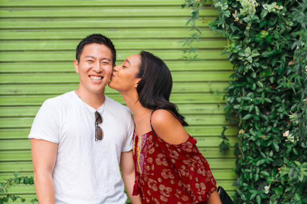 Girlfriend kissing her boyfriend A mixed-race girlfriend is kissing her boyfriend happily. cute couple stock pictures, royalty-free photos & images