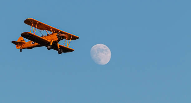 Colorful bi plane passing full moon with blue ske