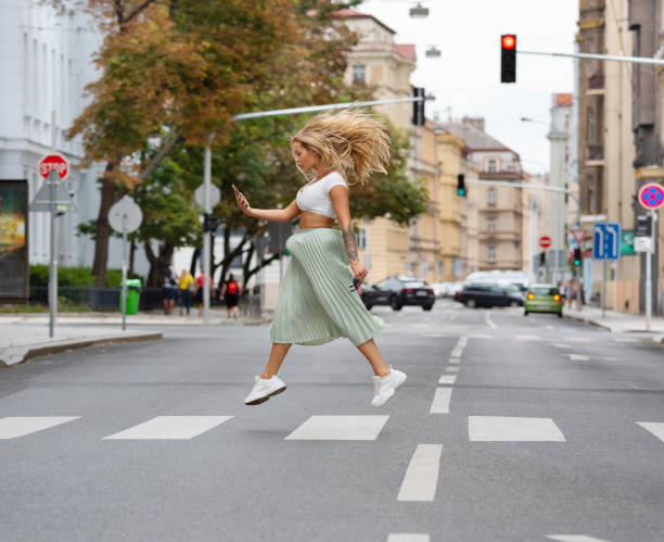 Blonde cool woman crossing street, jumping, hovering, checking phone Blonde cool woman crossing street, jumping, hovering, checking phone hopper car stock pictures, royalty-free photos & images