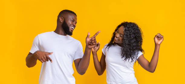 istock Joyful african american couple dancing on yellow studio background 1169954782