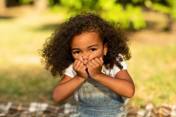 istock Little girl grimacing and touching cheeks in nature park 1169954789