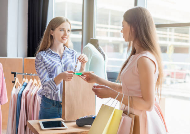 istock Smiling assistant accepting credit card and giving purchases to client 1169956750