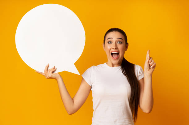 istock Excited Lady Holding Speech Bubble Pointing Finger Up, Yellow Background 1169956774