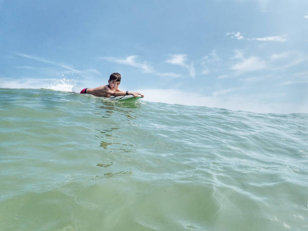 サウスベサニービーチデラウェア州のサーフボードに浮かぶ10歳の少年 - skimboard ストックフォトと画像