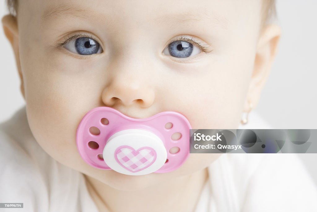 Baby with soother Frontal view of a cute baby girl with a soother in her mouth Pacifier Stock Photo