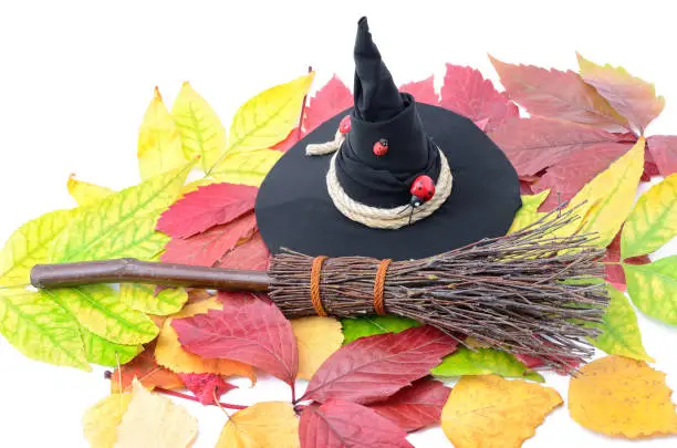 A witch's hat and a broom on the autumn leaves.