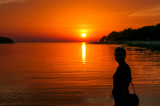 istock Vrsar - A girl enjoying the sunset by the beach 1169968329
