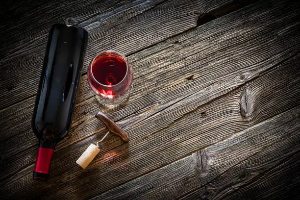 Photo of Wineglass, wine bottle, vintage corkscrew and cork stopper