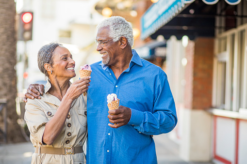 A senior black couple eating ice cream on the town at Christmastime.