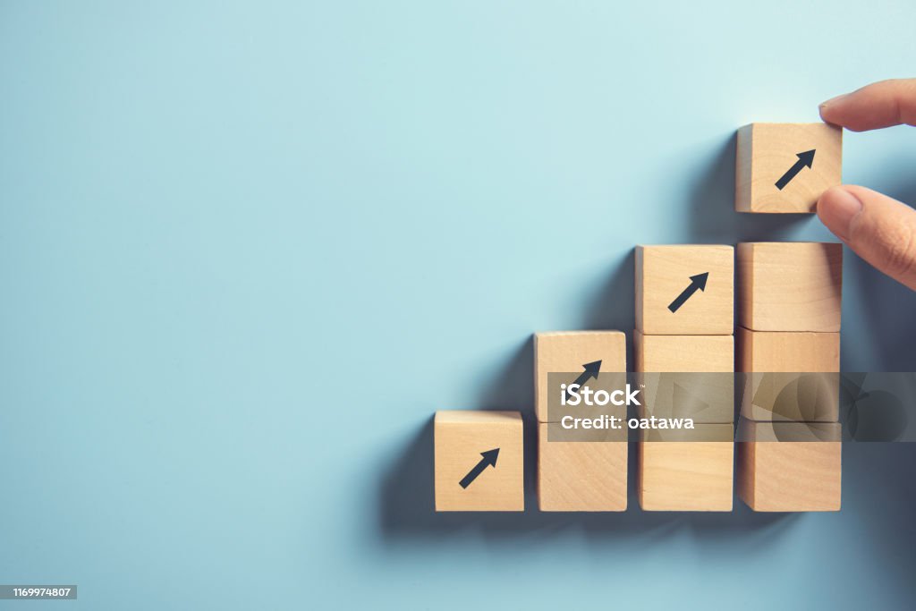Hand arranging wood block stacking as step stair on paper pink background. Business concept growth success process, copy space. Close up man hand arranging wood block stacking as step stair on paper pink background. Business concept growth success process, copy space. Growth Stock Photo