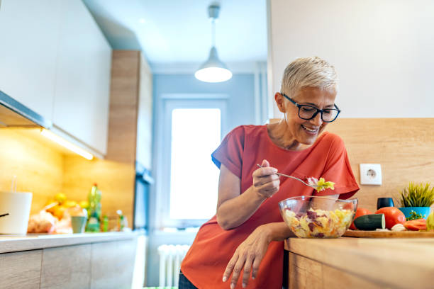istock Mature woman eating salad in kitchen 1169976703