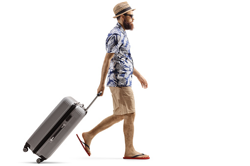 Full length profile shot of a bearded man with a suitcase walking isolated on white background