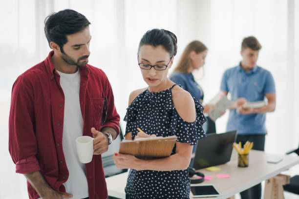istock Group of young creative people are standing, working and brainstorm which looking at paper work. Team of creative co-workers planning the work. felling be serious. Co working space concept 1169977614