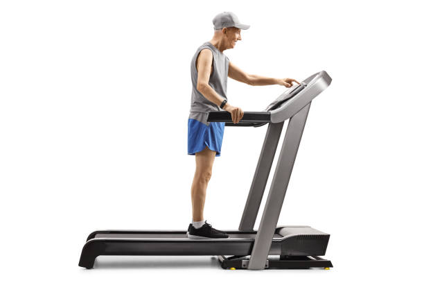 istock Senior man standing on a treadmill and pushing a button on display 1169978012