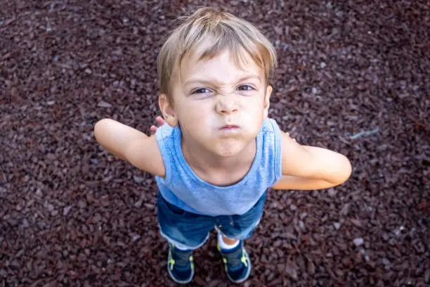 Very upset little child boy looking at the camera fro above